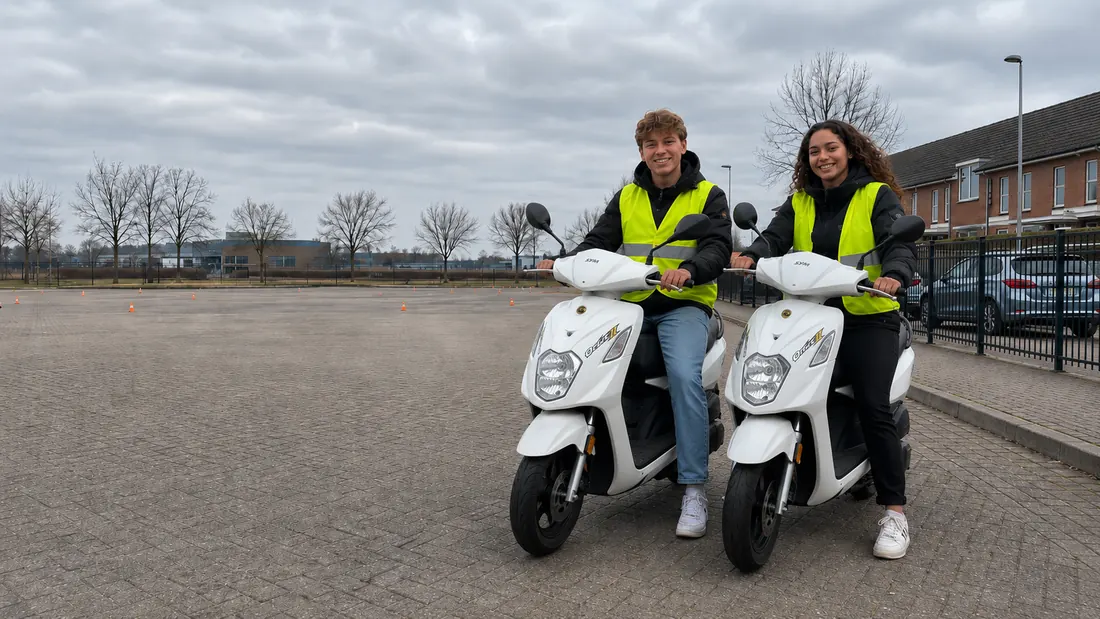 Twee leerlingen op witte lesscooters op het oefenterrein
